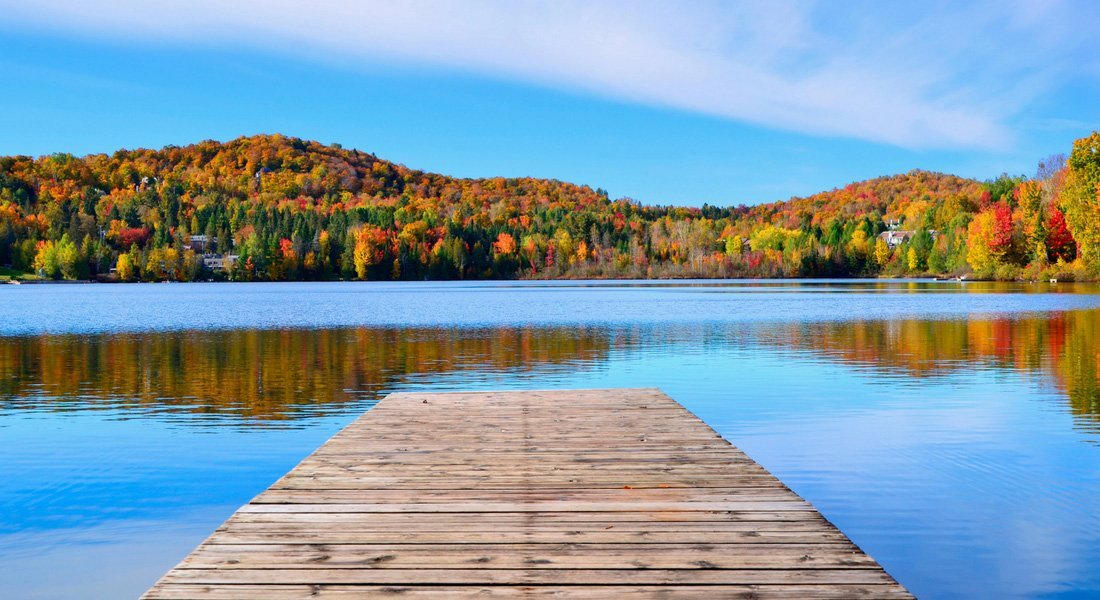Ponton en bois sur un lac entouré d'une forêt colorée lors de l'été indien au Canada