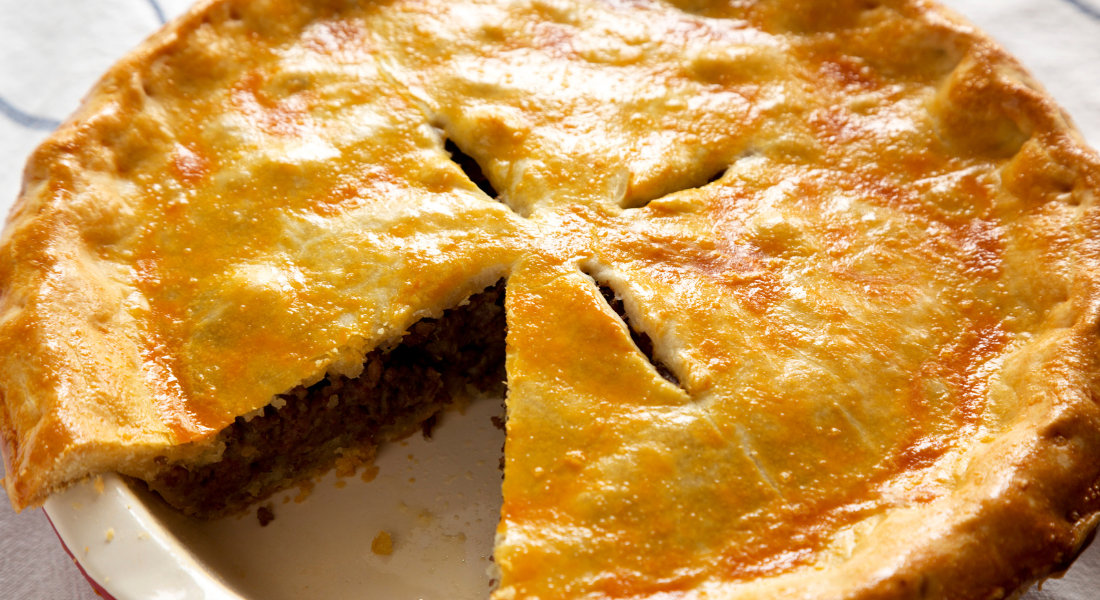 Tourtière québécoise servie dans une assiette avec sa croûte dorée