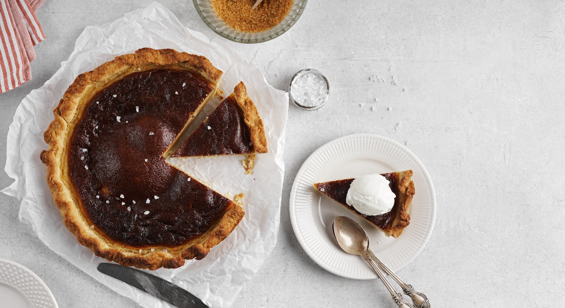 part de tarte au sucre servie dans une assiette sur lequel est posé une boucle de glace
