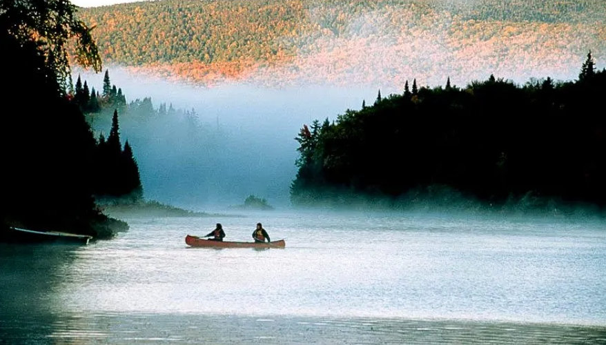 Lac Wapizagonke Une vue sur la lac et sur deux personnes dans un kayak avec du brouillard sur le lac