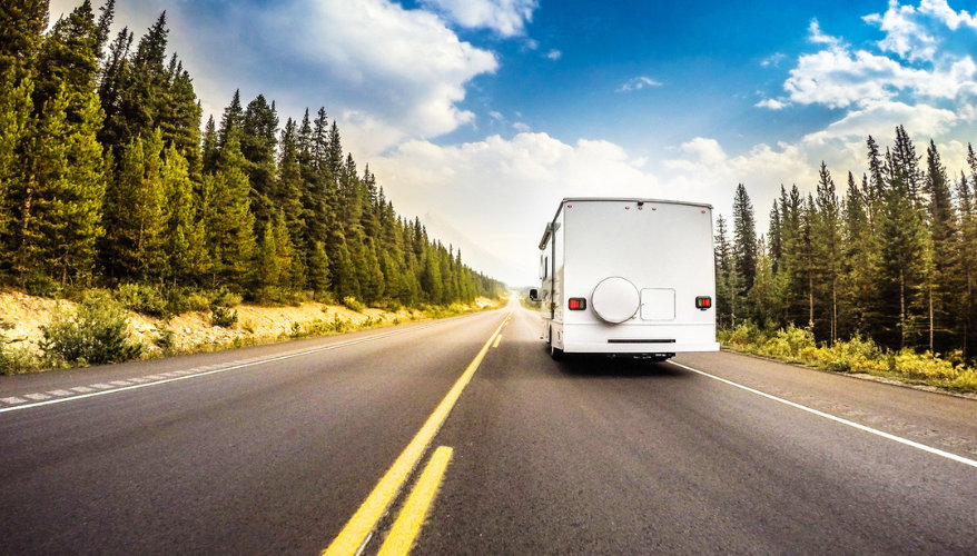La taille d’un RV peut impressionner avant le départ, mais la prise en main devient rapidement plus intuitive. Même avec un véhicule de 26 pieds, on peut vite trouver ses repères sur la route comme dans les campings. RV sur une route canadienne bordée de sapins