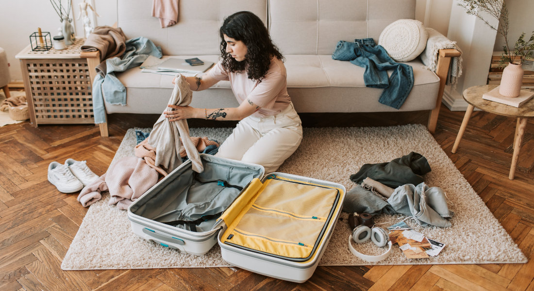 Un femme dans son salon en train de préparer sa valise avant un voyage