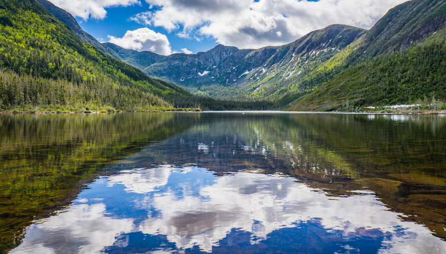 Hiking at Lac-aux-Américains Lac aux Américains surrounded by mountains and forests in Gaspésie National Park, Quebec.