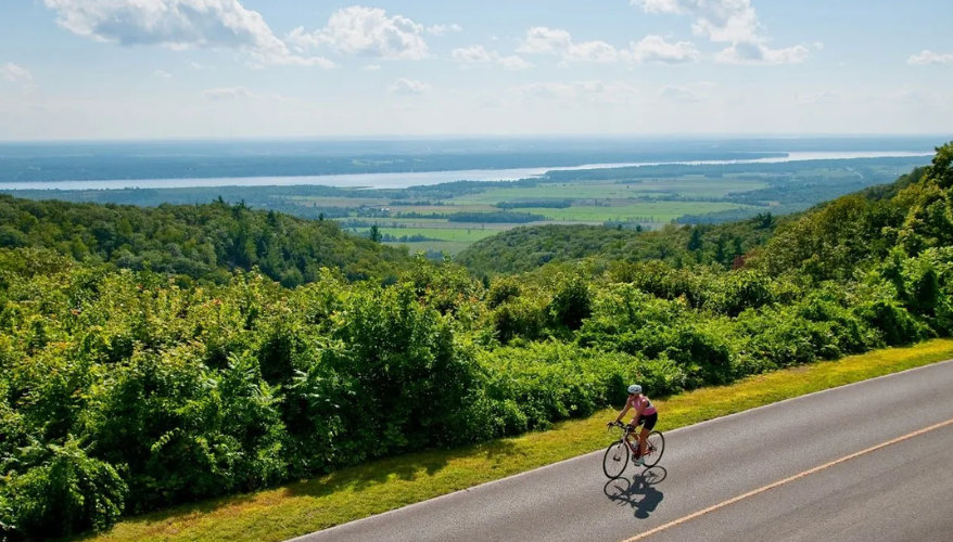 Cycling in Plaisance National Park Cyclist on a road surrounded by greenery with views of the Ottawa River in Plaisance National Park.