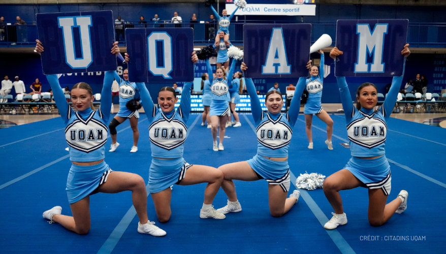 Cheerleading in Canada Four cheerleaders from UQAM University, each holding a sign with a letter of the university's name