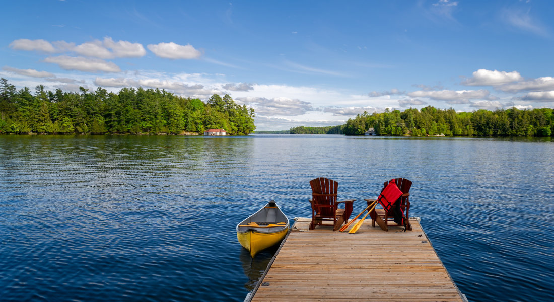 Un ponton sur un lac avec des chaises adirondacks et un canot