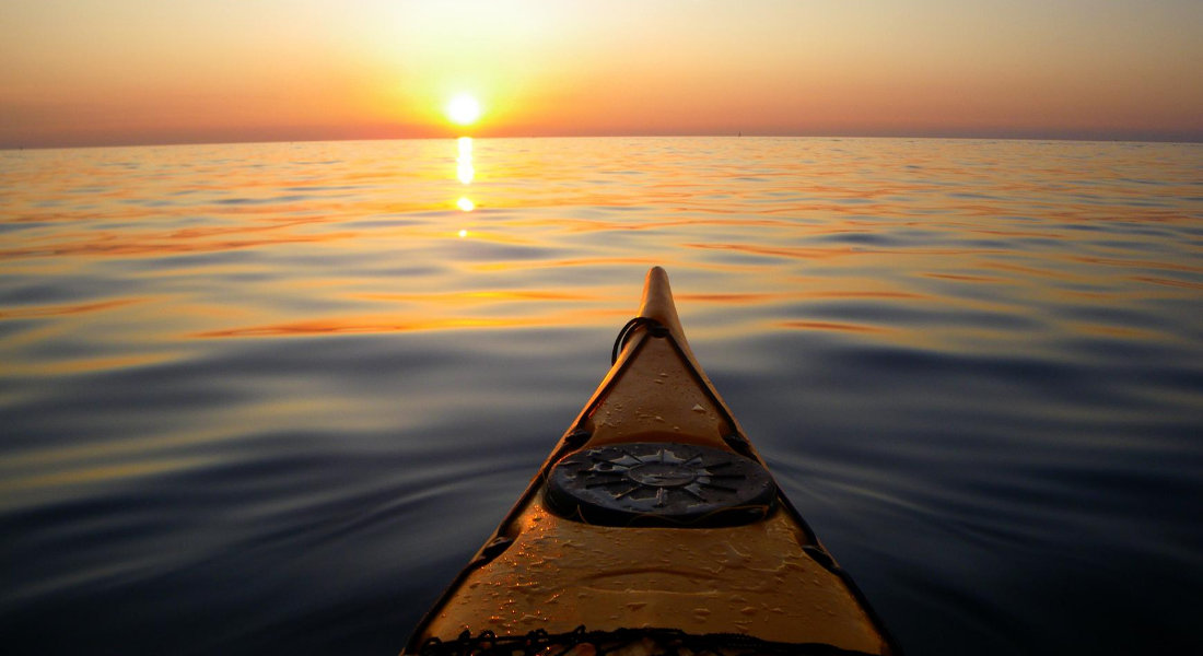 Pointe d'un kayak face au coucher du soleil
