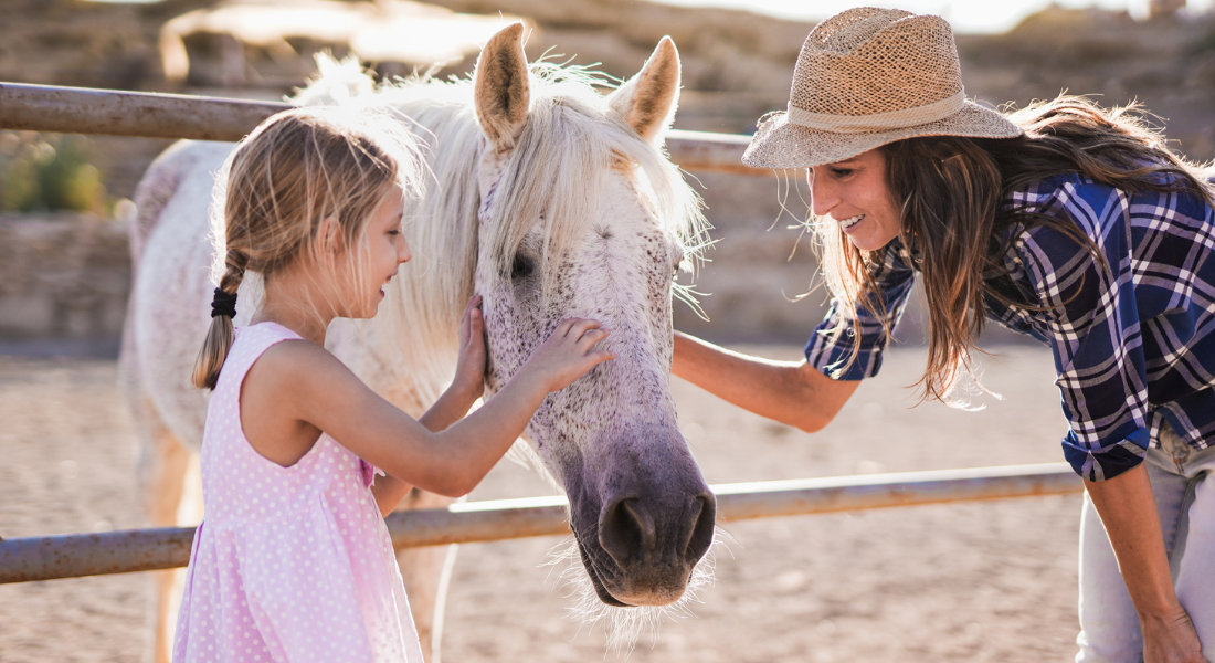 fillette et sa mère qui caresse un cheval dans un ranch