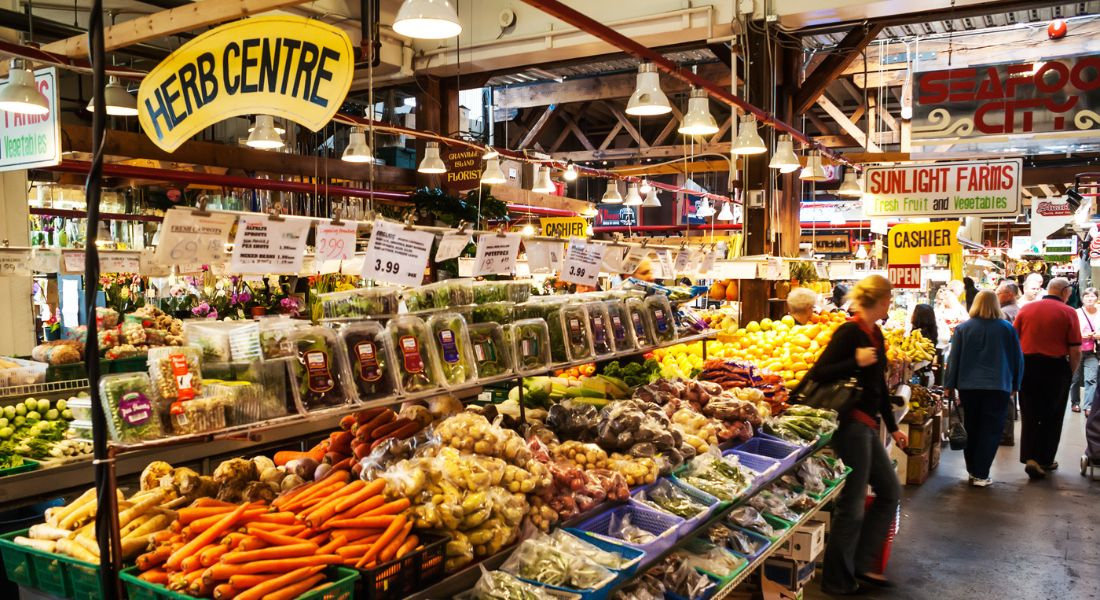 Marché dans une halle couverte avec des fruits et légumes au premier plan
