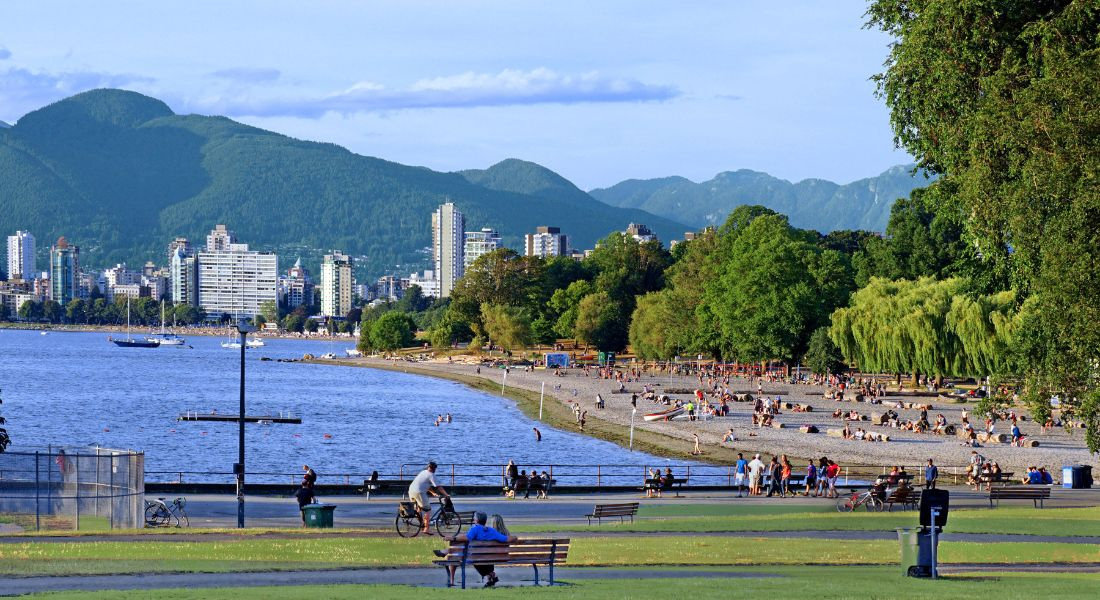 La plage urbaine de Kitsilano Beach avec les gratte-ciel de Vancouver et les montagnes en fond