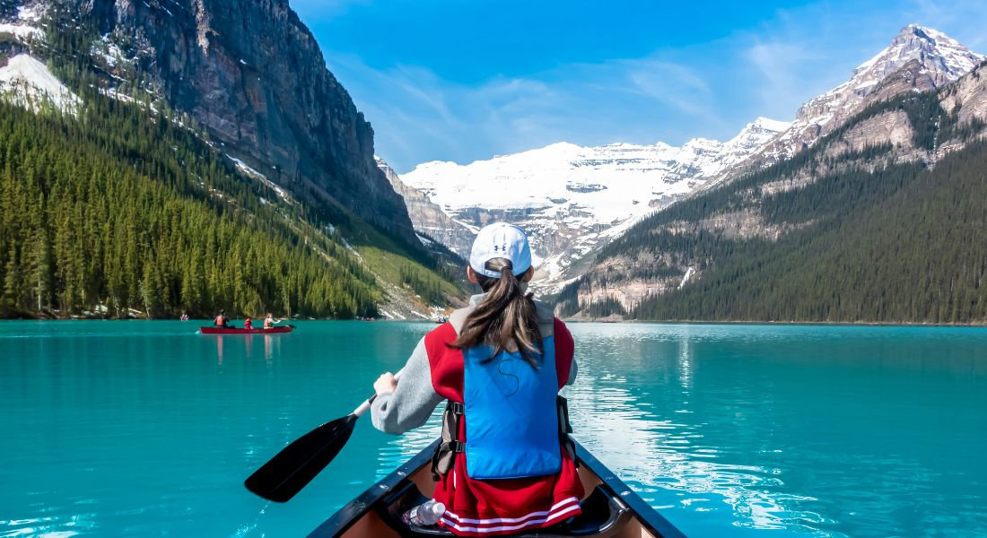 Jeune femme dans un canoé pagayant sur le lac Louise au Canada