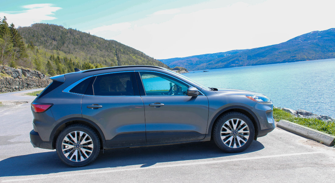 Consider the specifics of car hire in Canada SUV parked on a scenic road in Canada