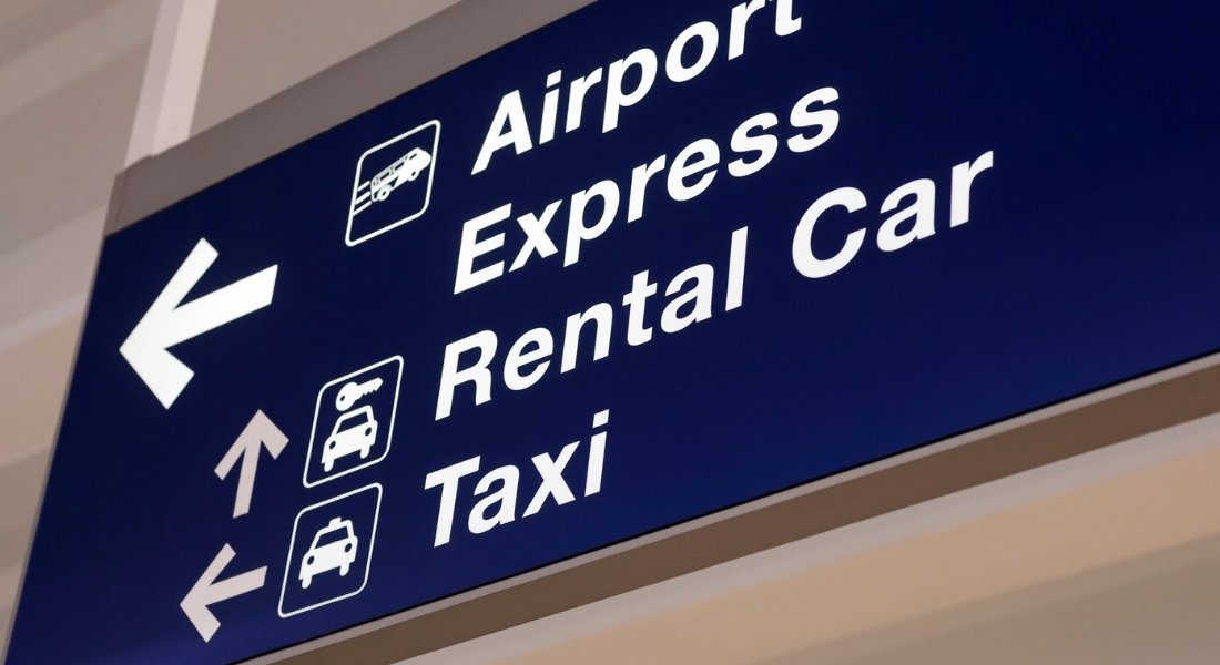 Location à l'aéroport ou en centre-ville? panneau de location de voiture à l'aéroport