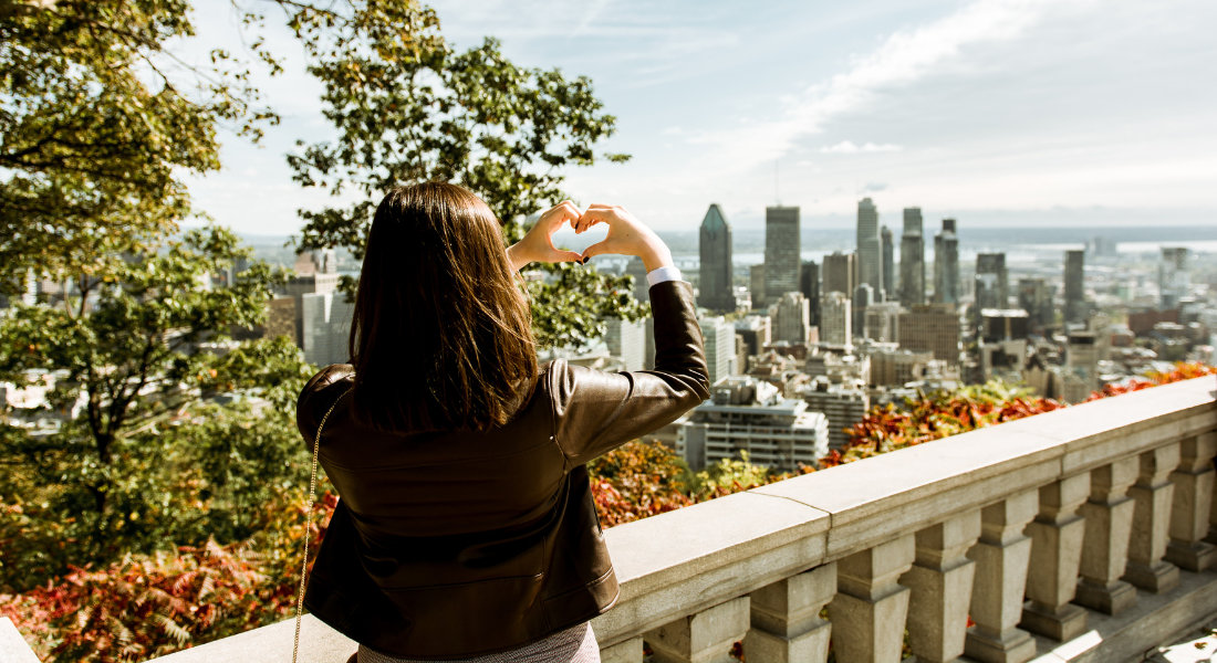 femme faisant un cœur avec ses mains sur le belvedere kondiaronk au mont royal avec vue sur montreal