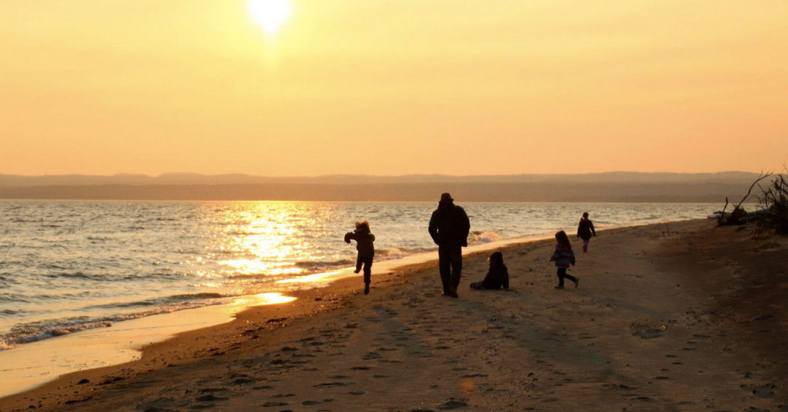 Famille sur une plage au coucher du soleil
