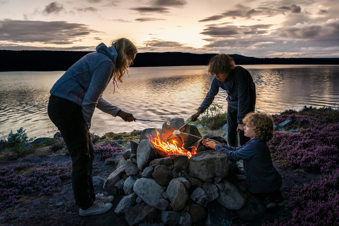 Marshmallows by the campfire Family toasting marshmallows around a campfire by a lake at sunset.