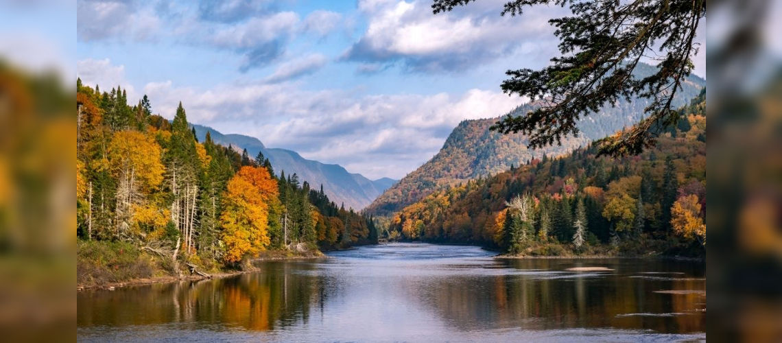 Rivière coulant au coeur du parc national de la Jacques-Cartier entouré de montagnes et d'arbres rouges orangés