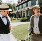 Deux personnages en costume devant un bâtiment du © Village Historique de Val-Jalbert