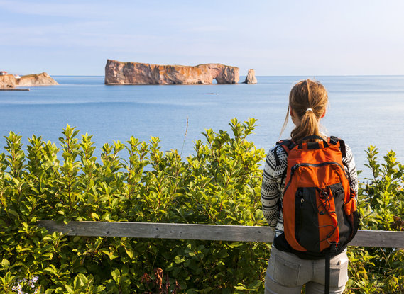 Young woman looking at the pierced rock in Gaspésie