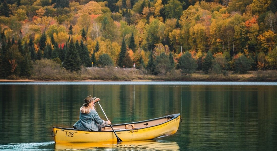 Faire du canot au Québec en automne Femme dans un canoé à l'automne