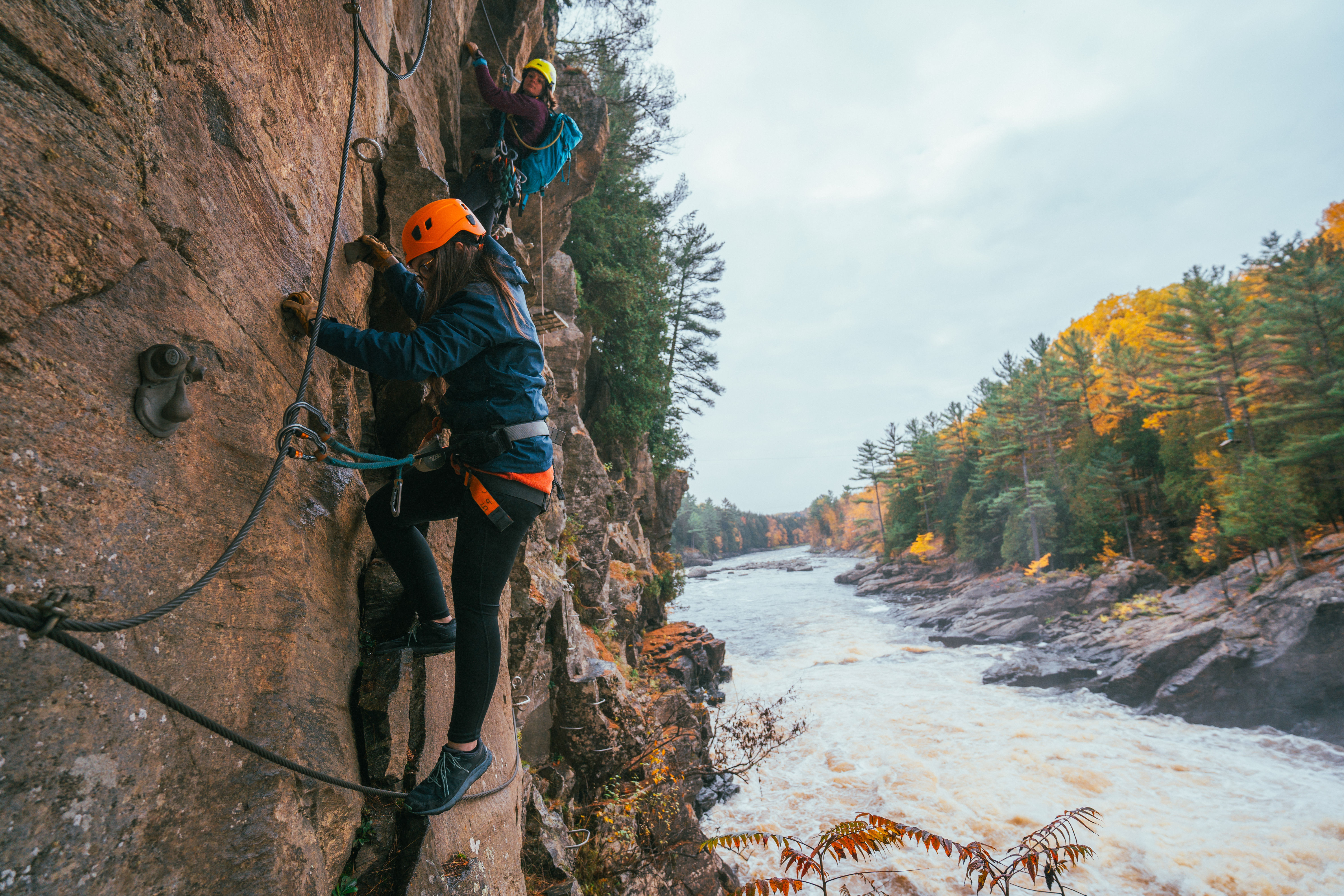 Via ferrata in Quebec at fall Two people doing a via ferrata above a river in autumn in Quebec
