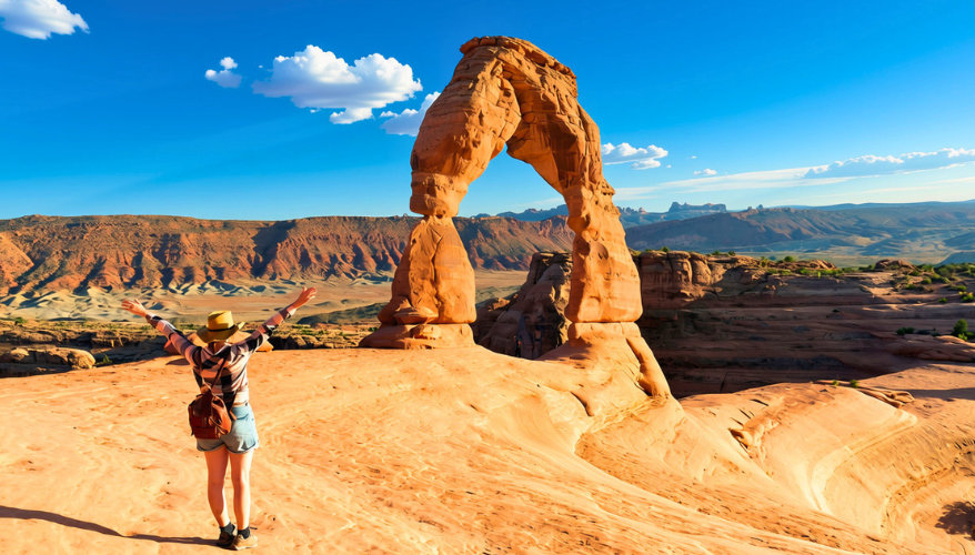 Delicate Arch A woman with her arms in the air in front of an arch.