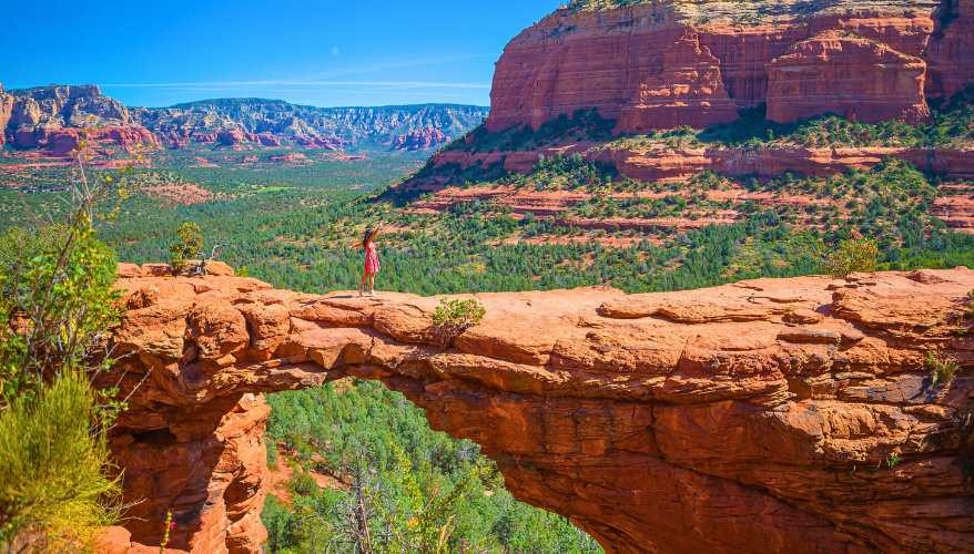 Devils Bridge A view of a natural bridge in Sedona with a woman standing on it.
