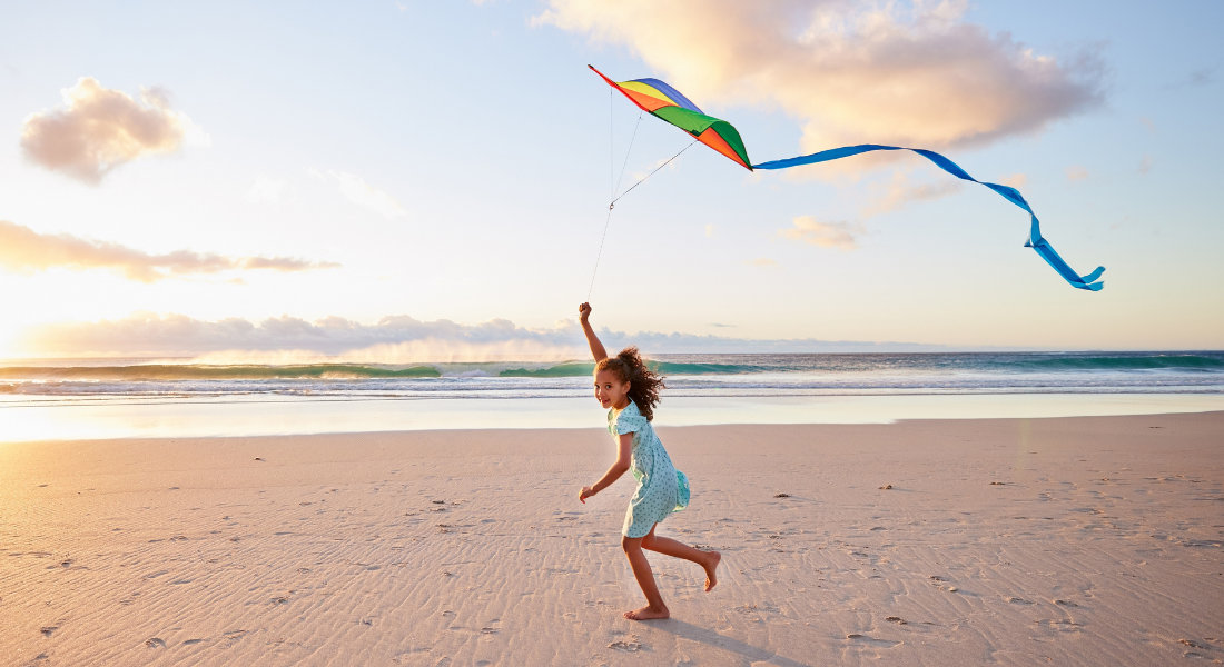 Enfant qui court avec un cerf volant sur la plage de Coopers Beach dans l'état de New York