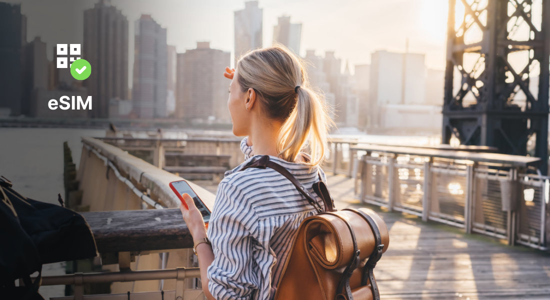 A traveller admires an American landscape while staying connected with an eSIM on her phone.