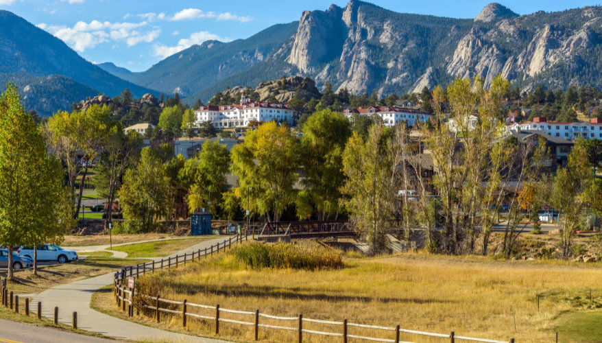 Au pied du Rocky Mountain National Park, la ville d'Estes Park est dominée par le célèbre Stanley Hotel, qui a inspiré Stephen King pour son roman Shining. C'est également la principale porte d'entrée est du parc national et une étape incontournable d'un Vue sur Estes Park avec le Stanley Hotel et les montagnes du Rocky Mountain National Park en arrière-plan, dans le Colorado.