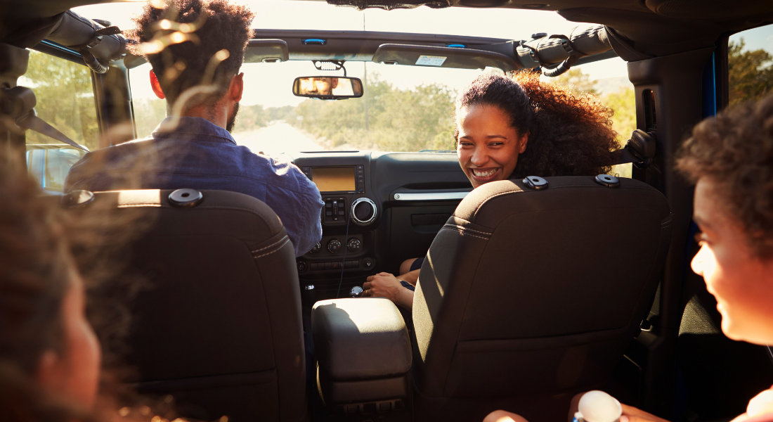 Anticiper la réservation et adapter le véhicule à son itinéraire Femme passagère qui se retourne pour regarder ses enfants à l'arrière de la voiture