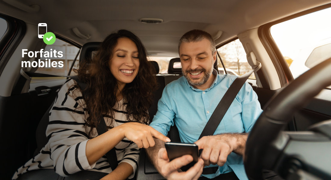 Un couple souriant dans sa voiture consulte un téléphone grâce à un forfait mobile français activé aux États-Unis.