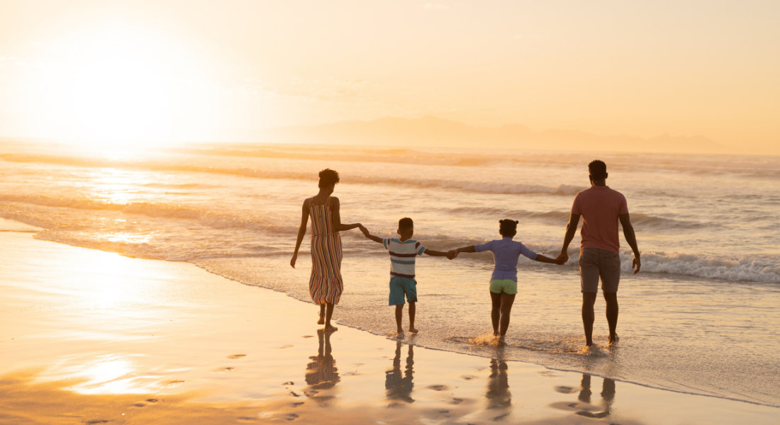 Famille avec enfant qui marche les pieds dans l'eau au coucher de soleil sur la plage de Popham Beach State Park