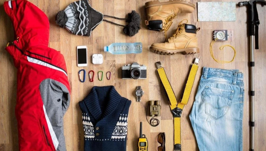 What to pack Table laid out with a winter hat, snow boots, jeans, a coat and other cold weather gear