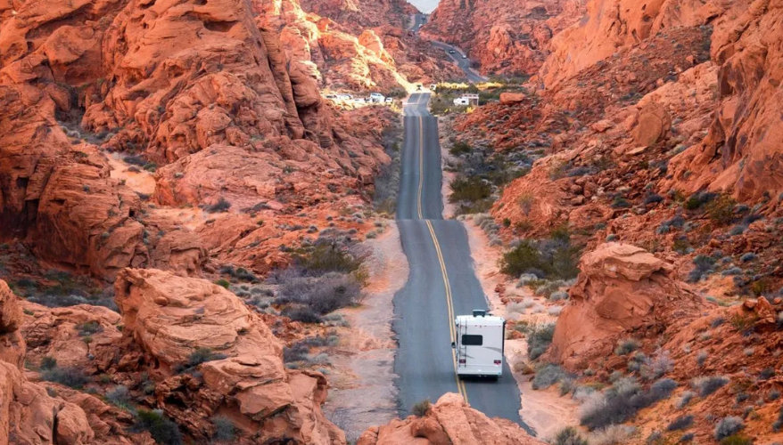 camping-car en toute nature Un camping car sur une route bordé par des roches oranges