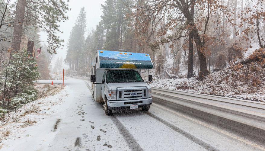 Motorhome travel in the American West in winter Cruise America motorhome parked beside a snowy road in an American forest