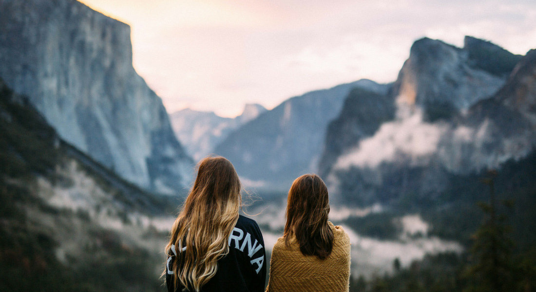 Warm hospitality Two women from behind watching the sunset at Yosemite